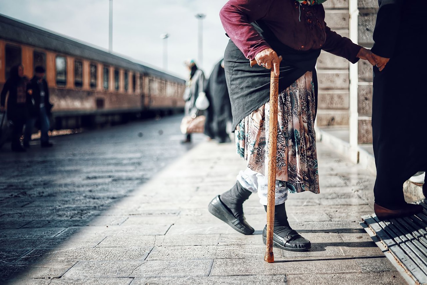 Une femme âgée avec une canne qui marche accompagnée de quelqu'un